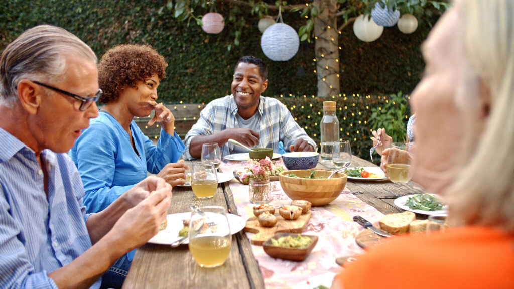 Family members joyfully gathering for a meal in the backyard